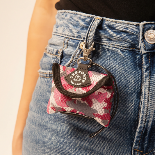 Lupiora TRE PONTI Kotbeutelspender aus rosa-grauem Netzgewebe mit Karabiner an einer Jeans befestigt